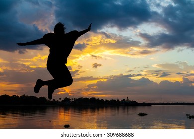 Silhouette Lady Jumping Happy Beside The River At Sunset 