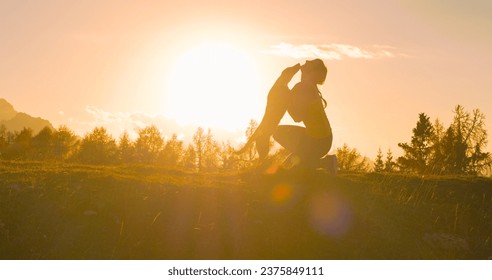 SILHOUETTE, LENS FLARE: Adorable moment between a happy dog and a loving owner. Doggo with wagging tail and playful young woman on top of a picturesque mountain in magnificent autumn sunset light.