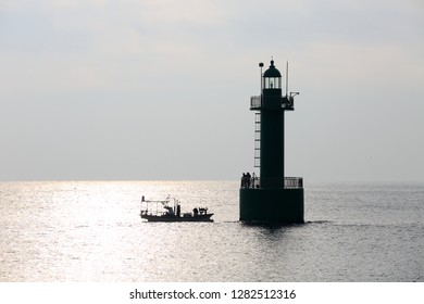 silhouette of lighthouse and boat on the sea in the morning