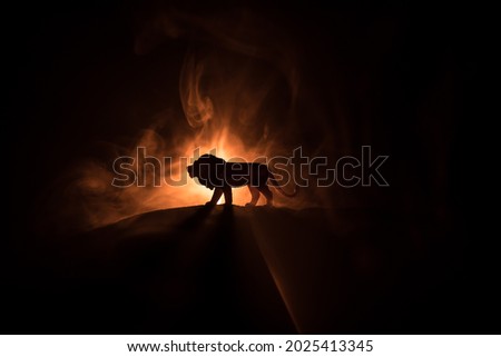 Silhouette of a lion miniature standing in dark. Creative decoration with colorful backlight with fog. Selective focus