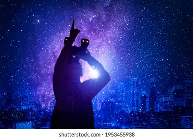 Silhouette of little boy using binoculars while pointing at the night sky and standing with milky way background - Powered by Shutterstock