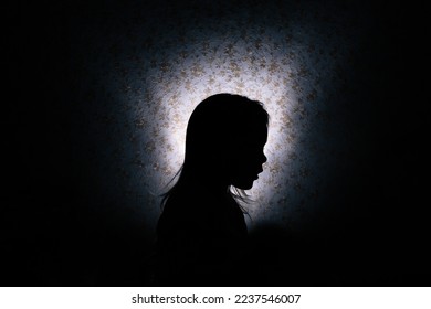 Silhouette of a little girl in the dark.
