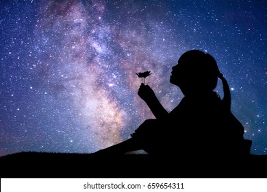 Silhouette of little girl holding a flower at the stars background - Powered by Shutterstock