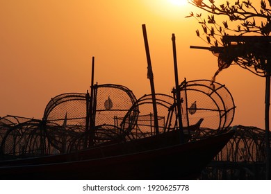 Silhouette of lobster pots or traps on fishing boats against an orange sunset sky, southeast Asia