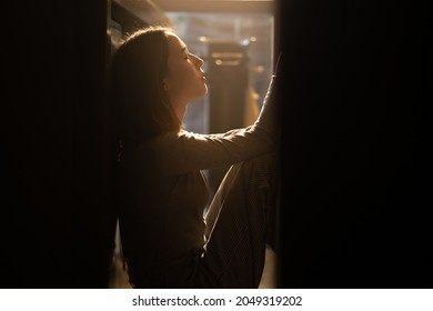 Silhouette Of Loneliness Asian Woman Sitting On The Floor With Hugging Herself. Depressed Female Living Alone In The Dark Room And Think Of Life Problems. Mental Health And Social Issue Concept.