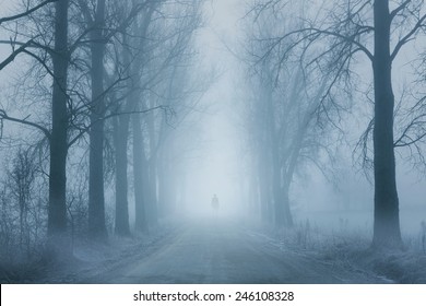 Silhouette of a lonely man standing on the foggy road - Powered by Shutterstock