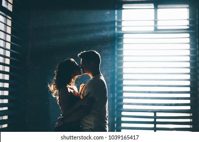 Silhouette Of Lovers Standing Near Window And Looking To Each Other. Magic Light.  
Sunlight Through Smoke.