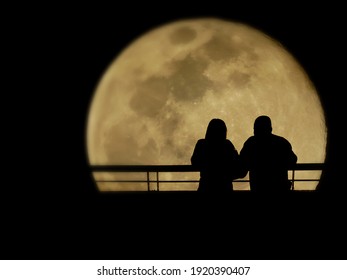 Silhouette of lovers watching full moon in the romantic night