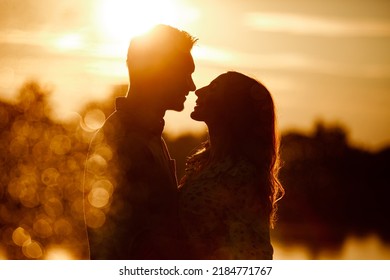 silhouette of loving couple hugging on the lake at sunset. Beautiful young couple in love walking on the shore of the lake at sunset in the rays of bright light. copy space. selective focus. - Powered by Shutterstock