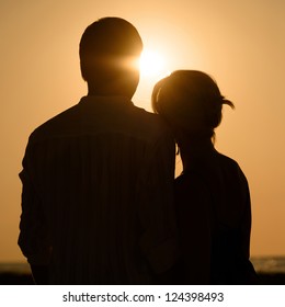 Silhouette of loving couple over orange sunset background