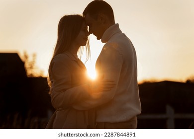 Silhouette of loving couple couple at sunset is hugging and touching nose to nose outdoors at park. Young man and woman falling in love have romantic date on Valentine's day. - Shutterstock ID 2287844891