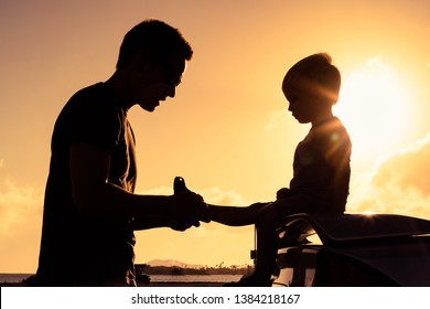 Silhouette of loving father putting his little boys shoes on.  - Powered by Shutterstock