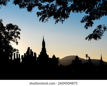A silhouette of a majestic Lankan style chedi during sunrise or sunset, reflecting the grandeur of the ancient Sukhothai Kingdom at Sukhothai Historical Park, a UNESCO World Heritage Site in Thailand