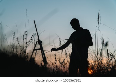 Silhouette of a male artist painting a sunset landscape outdoors in a natural landscape - Powered by Shutterstock