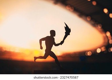 Silhouette of Male Athlete Carrying the Torch Relay, Illuminating the Modern Track and Field Stadium. A Captivating Snapshot for the Summer Game 2024 in Paris. - Powered by Shutterstock