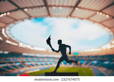 Silhouette of male athlete holding torch relay. Modern Track and Field Stadium in background. Photo for Summer game in Paris - Powered by Shutterstock