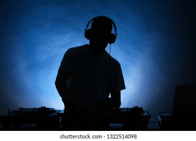 Silhouette of male DJ playing music on color background - Shutterstock ID 1322514098