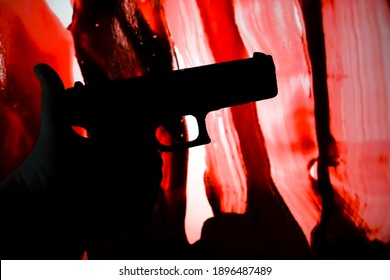 Silhouette Of Male Hand  Holding Gun On Red Bloody Background