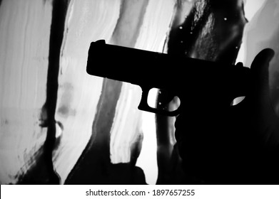 Silhouette Of Male Hand  Holding Gun On White And Black Background