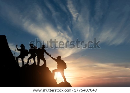 Silhouette male hiker groups celebrating success on top of a mountain.