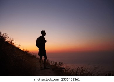 Silhouette of male hiker on trail overlooking ocean at sunset - Powered by Shutterstock