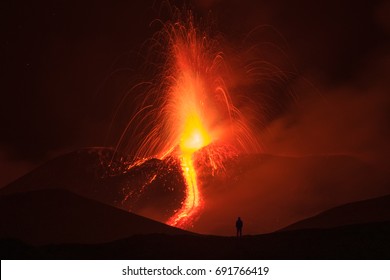 A silhouette of a man admiring the eruption of the mount Etna.