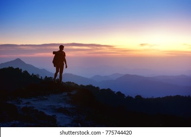 Silhouette Of Man With Backpack At Mountain Top On Background Of Sunset Mountains