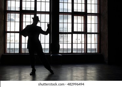 Silhouette Of Man In Black Suit And Hat Dancing Tango In Room With Big Window
