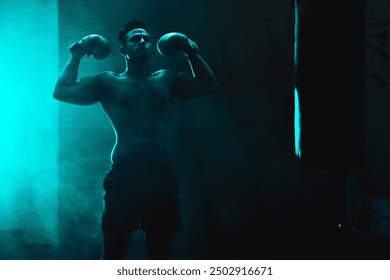 Silhouette, man and boxer with boxing gloves at gym for martial arts, competition or training. Active, strong male person or fighter with flex by punching bag for muay thai practice at health club - Powered by Shutterstock