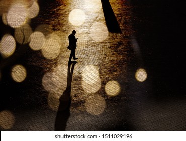 Silhouette Of A Man In A Business Suit On The Square In Abstract Bokeh. Stranger, Anonymous, Spy. Dark Photo Of A Man With Shadows In A Low Key.