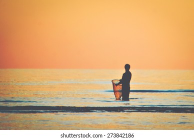 Silhouette of a man carrying a Sabah local fishing net called "siyud". "Siyud" is used to catch small fish and prawns along the sea shore. Image in faded Instagram effect creating retro look.  - Shutterstock ID 273842186