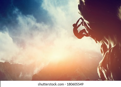 A silhouette of man climbing on rock, mountain at sunset. Adrenaline, strenght, ambition - Shutterstock ID 180605549