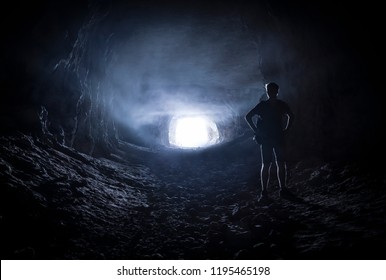 Silhouette of a man in the corridors of a creepy dark cave. - Powered by Shutterstock