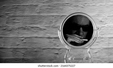 Silhouette Of A Man With A Diatonic Harmonica In His Hand Is Reflected In The Mirror On A Gray Blurred Brick Wall Background, Copy Space, Banner Concept, Backgrounds And Textures