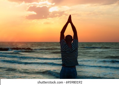 Silhouette of a man does yoga at sunset