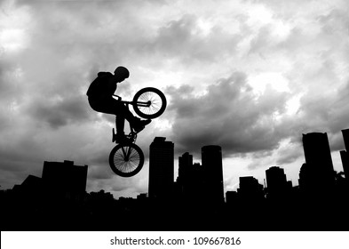 Silhouette of a man doing an extreme jump with a mountain bike .
