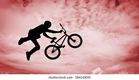  Silhouette of a man doing an jump with a bmx bike. 
