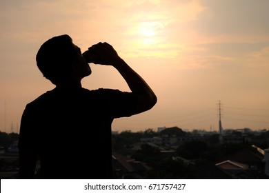 The Silhouette Of A Man Drinking A Refreshing Can Of Beer On A Sunset Background