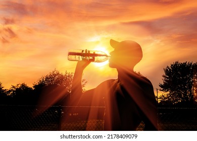Silhouette of a man drinking water during heat wave - Shutterstock ID 2178409079