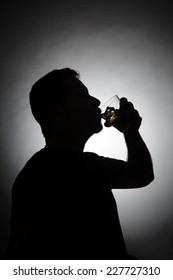 Silhouette of man drinking whiskey.