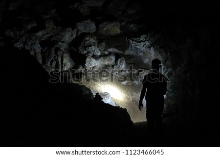 Silhouette of a man exploring a cave with a torch