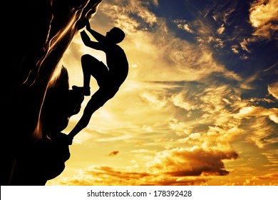 A Silhouette Of Man Free Climbing On Rock, Mountain At Sunset. Adrenaline, Bravery, Leader.