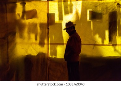 Silhouette of a man in a hat against a wall at night. Blur background with shallow depth