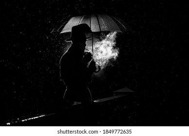 silhouette of a man in a hat under an umbrella Smoking a cigarette at night in the rain in the old crime Noir style