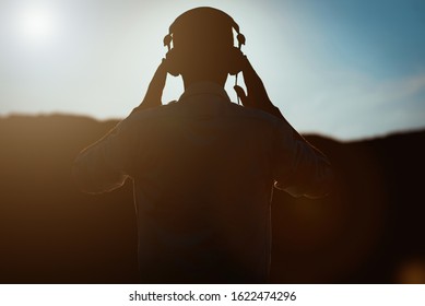 Silhouette Of Man With Headphones On Sunset Sky Background. Silhouette Of Happy Man Listening Music