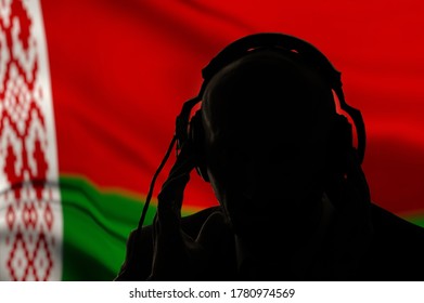 Silhouette eines Mannes in Kopfhörern, Geheimagent bei Abhörmaßnahmen, Spionagedienst und Nachrichtendienst, weißrussische Flagge, Beleuchtung