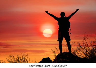 silhouette of man hiker standing on rocky mountain peak with sunset golden sky feeling of freedom - Shutterstock ID 1622565097