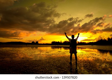 Silhouette of Man with his hands up watching the sun set
