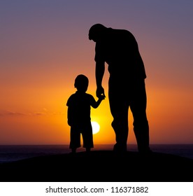 Silhouette of a man and his son with sunset background.