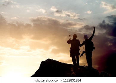 Silhouette of man hold up hands on the peak of mountain - Shutterstock ID 1122831284